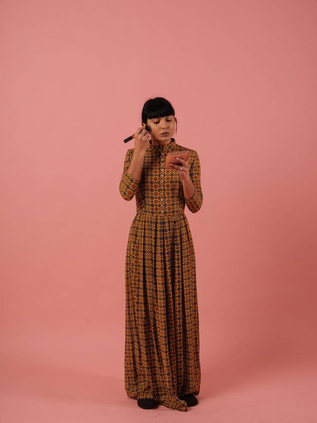 混血女性ローズ ピンクの背景ブラシでメイク - 写真・画像