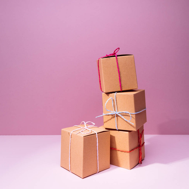 Craft cardboard gift boxes on the solid pink background. Holiday - Фото, зображення