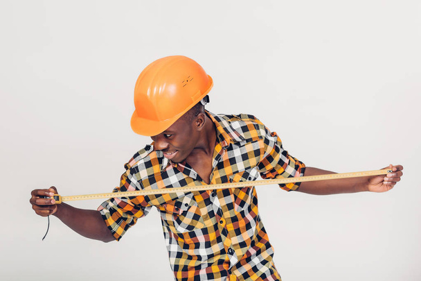 African-American builder uses measuring tape - Zdjęcie, obraz