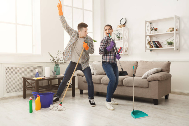 Nuori pari siivoamassa kotia, leikkimässä mopilla
 - Valokuva, kuva