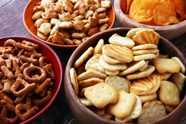 Zoute snacks. Zoutjes, chips, crackers in houten kommen. - Foto, afbeelding