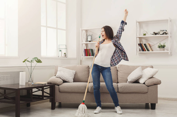 Femme heureuse nettoyant la maison avec de la serpillière et s'amusant
 - Photo, image