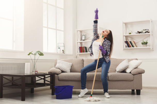 Счастливая женщина убирает дом шваброй и веселится
 - Фото, изображение