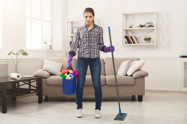 Женщина с оборудованием для уборки готова к уборке комнаты
 - Фото, изображение