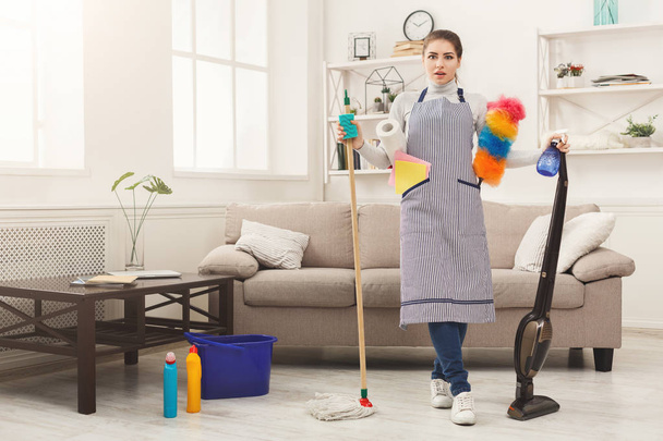 Mulher chocada casa de limpeza com muitas ferramentas
 - Foto, Imagem