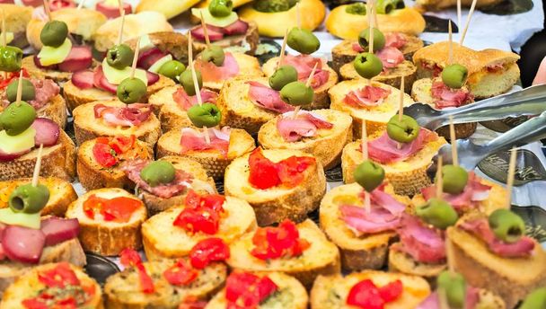 aperitief buffet met voorgerechten en bruschetta met tomaten, olijven en vleeswaren - Foto, afbeelding