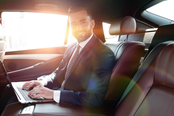 smiling businessman sitting in the back seat of a prestigious ca - Φωτογραφία, εικόνα