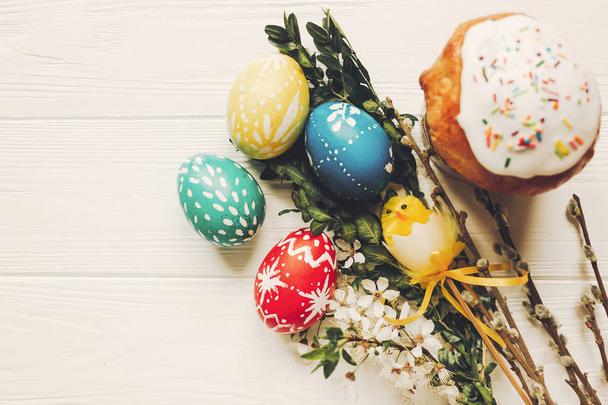 κομψό αυγά του Πάσχα και Πασχαλινό ψωμί τούρτα και λουλούδια σε φόντο ξύλινη επίπεδη lay. σύγχρονη φυσική πολύχρωμα αυγά βαμμένα. χώρο για το κείμενο. ευτυχισμένο Πάσχα ευχετήρια - Φωτογραφία, εικόνα