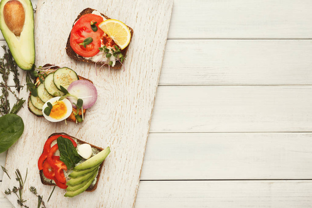 Variedad de sándwiches vegetarianos saludables en madera blanca, vista superior
 - Foto, Imagen