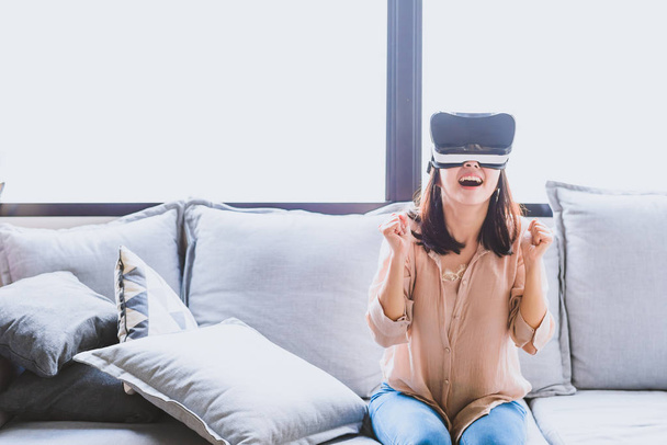 Знімок веселої і збудженої жінки в гарнітурі VR у вітальні
 - Фото, зображення