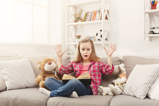 Stupita bambina con libro e i suoi giocattoli preferiti a casa
 - Foto, immagini