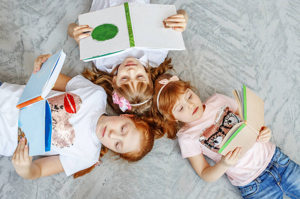 Μια ομάδα παιδιών καθορίζει στο πάτωμα και διαβάζει βιβλία. Το conce - Φωτογραφία, εικόνα