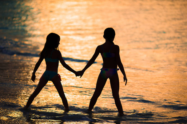 Красивые маленькие девочки на пляже с красивым красочным закатом
 - Фото, изображение