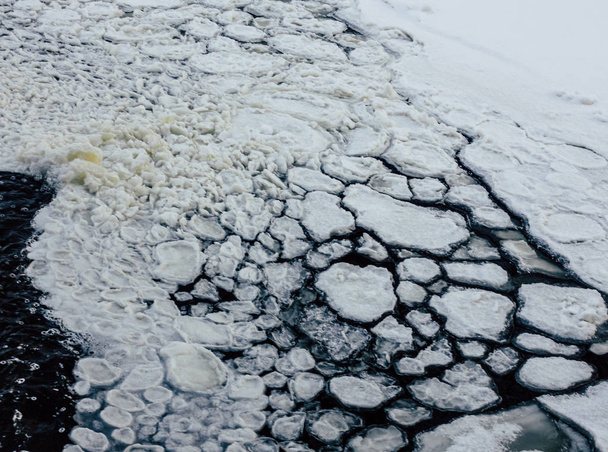 kleine gefrorene Eiswürfel in einem Fluss an bewölkten Tagen mit dunklem Wasser im Hintergrund - Nahaufnahme - Foto, Bild