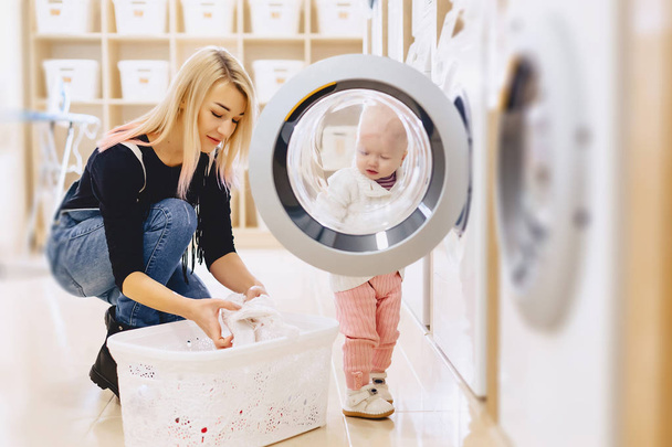Mãe e bebê na lavanderia levar as coisas e jogar
 - Foto, Imagem