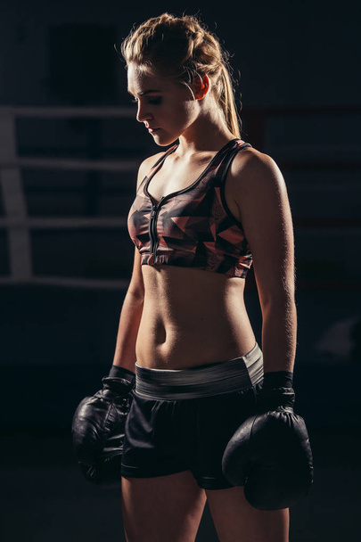 Female Boxer wearing gloves posing in boxing studio - Fotografie, Obrázek