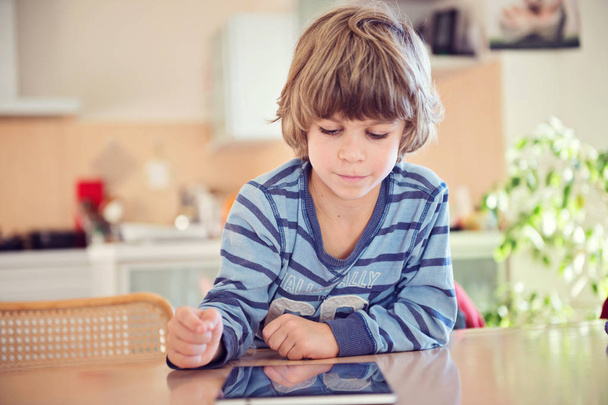 Jongetje met digitale pad aan de tafel spelen. - Foto, afbeelding