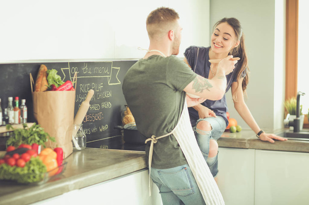 Couple cooking together in their kitchen at home - Фото, изображение