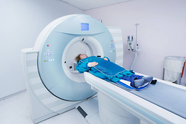 Жінка-пацієнтка, яка проходить КТ - комп'ютеризована томографія сканування в лікарні. Пацієнт, який носить свинцевий фартух для покриття життєво важливих органів
. - Фото, зображення