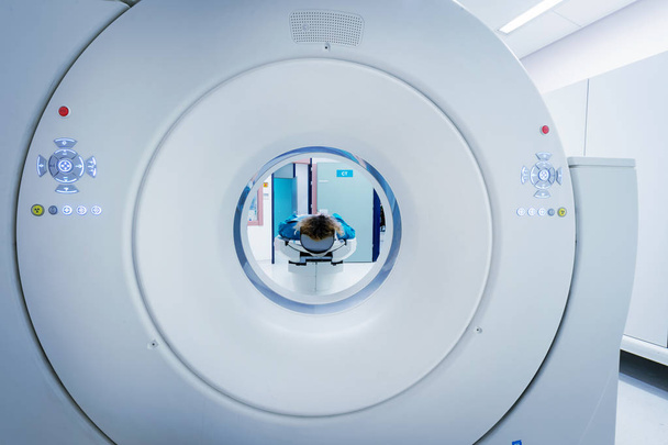 Vrouwelijke patiënt ondergaat, Ct - gecomputeriseerde tomografie Scan in het ziekenhuis. Patiënt dragen lood schort ter dekking van de vitale organen. Kijk door de buis van het apparaat. - Foto, afbeelding