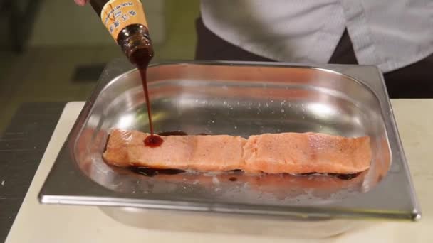Cook je lití čínské omáčky z láhve na lososový filet v kovovou desku - Záběry, video
