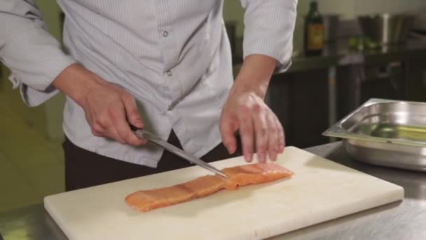 Specialista culinario sta affettando un pezzo di lox fresco crudo su una tavola di legno
 - Filmati, video