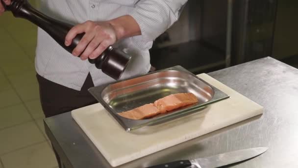 Chef-kok is de toevoeging van wat zout molen draaien over zalm stuk over een professionele keuken - Video