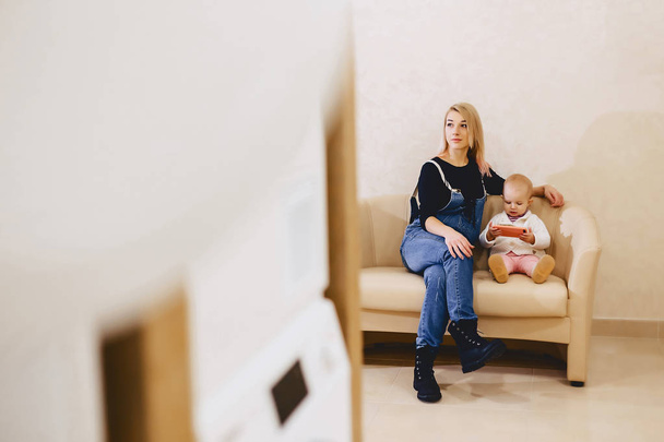 A woman with a child is sitting on the sofa in the laundry in th - Foto, imagen