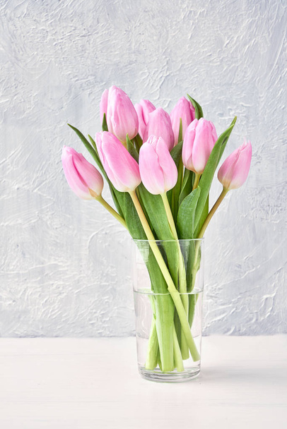 Ramo de tulipanes rosados en jarrón de vidrio sobre mesa blanca. Copiar espacio
 - Foto, Imagen