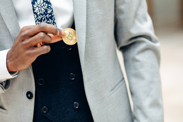 African Man pick bitcoin from suit pocket . Man puts bitcoin in pocket - Fotoğraf, Görsel