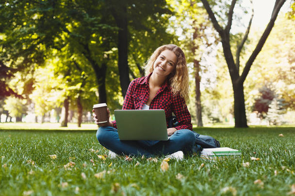 Beautiful young woman using a laptop outdoors - Fotoğraf, Görsel