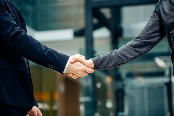 two multiracial businessmen handshaking in modern office for end of great deal - Фото, изображение