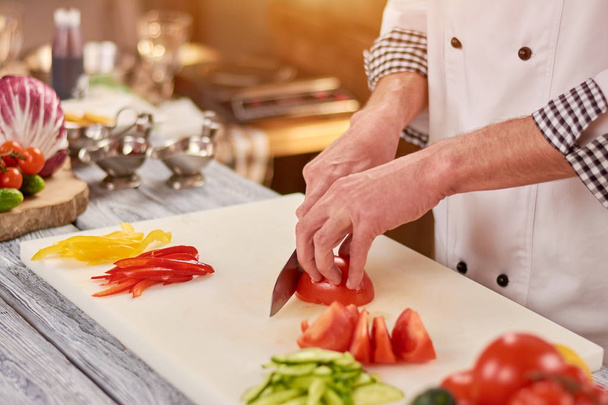 Chef slicing tomato on cutting board. - Photo, Image
