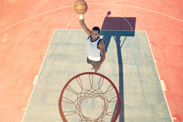 High angle view of basketball player dunking basketball in hoop - 写真・画像