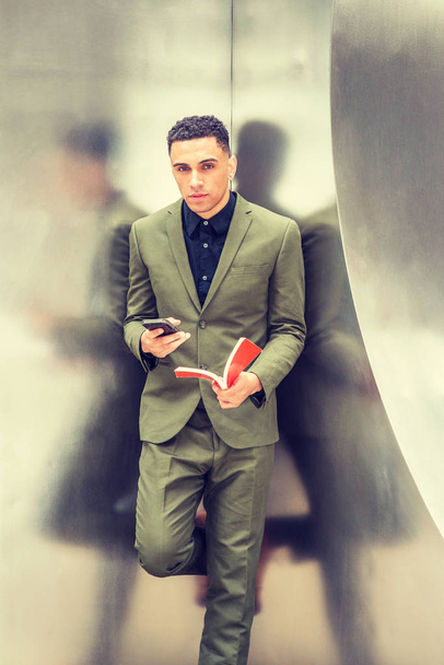 junger amerikanischer Geschäftsmann liest Buch, SMS auf Handy. - Foto, Bild