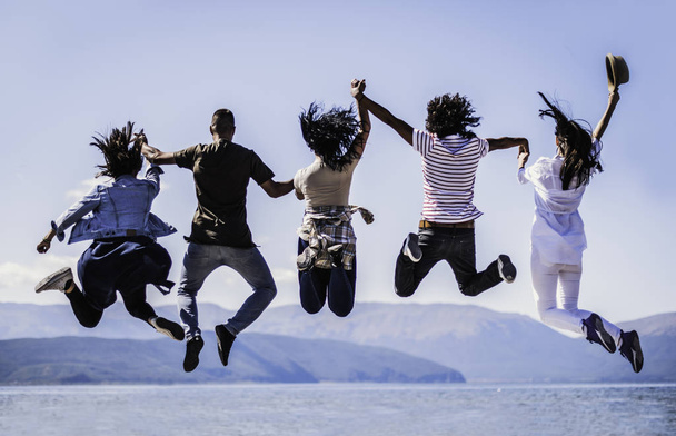 Grupo de jóvenes felices saltando sobre un fondo azul del cielo
 - Foto, Imagen