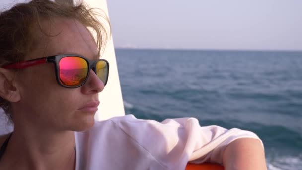 Eine schöne Frau steht auf dem Heck des Schiffes. Wellen im Hintergrund, Zeitlupe, 4k - Filmmaterial, Video