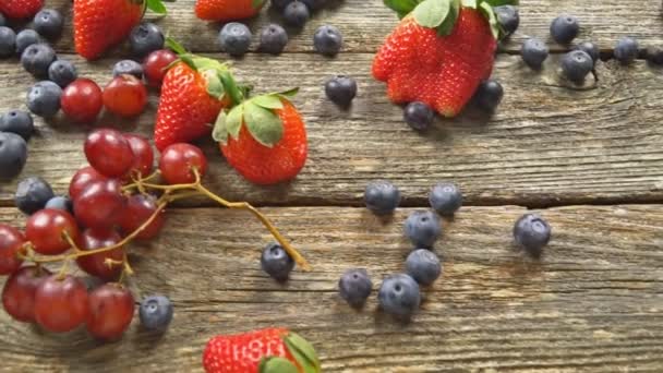 Bosbessen druif aardbeien vruchten op houten plaat op houten achtergrond Slow-Motion hd video - Video