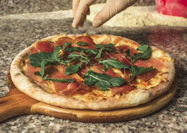 Zubereitung von Pizza mit Schinken und Rucola - Foto, Bild