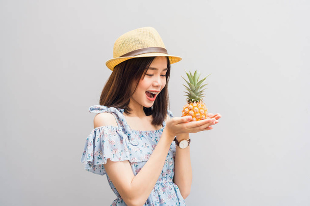 Young girl happy smile and cheerful in blue dress, hold two pineapple in hand. Concept summer travel. - Photo, Image
