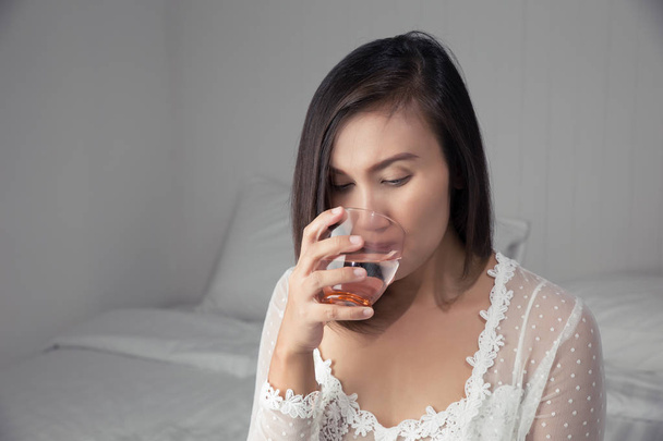 Asyalı kadın beyaz gecelik içme suyu - Fotoğraf, Görsel
