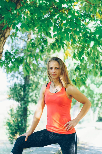 Jovem mulher fitness se exercitando no parque com telefone celular e fones de ouvido
 - Foto, Imagem