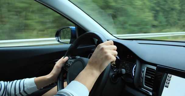 Fingers of drivers hands grip the steering wheel in car on the speed  - Photo, Image