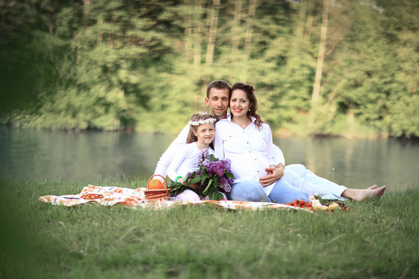 happy family: father,pregnant mother and little daughter on a pi - Zdjęcie, obraz