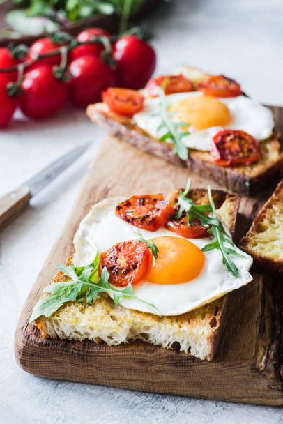 Breakfast toast with egg, arugula and roasted tomato, closeup view - Foto, imagen