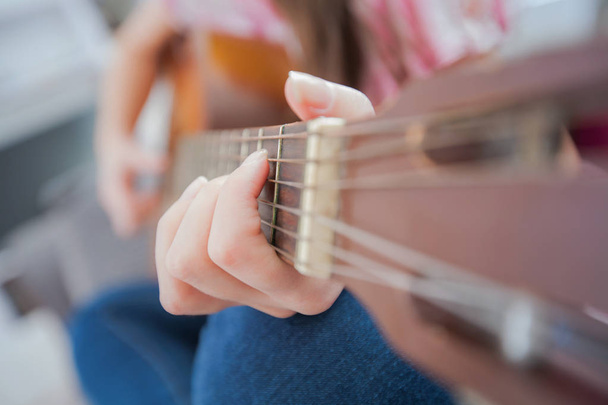 Μουσική νεαρή γυναίκα, γυναικείο χέρι παίζει κλασική κιθάρα, αγνώριστος άτομα  - Φωτογραφία, εικόνα