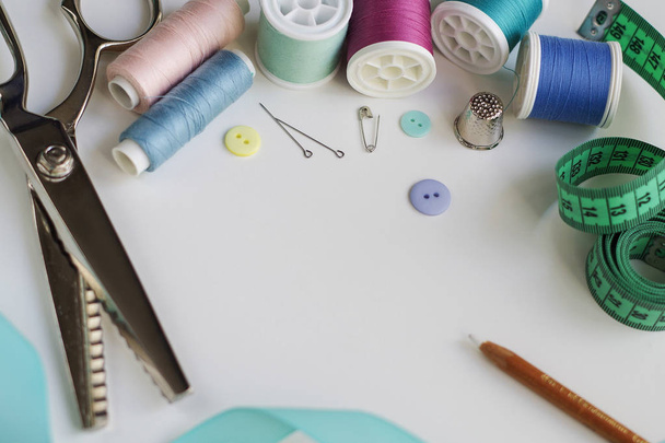 Spools of thread and basic sewing tools including pins, needle, a thimble, and tape measure. Copy space - Foto, imagen