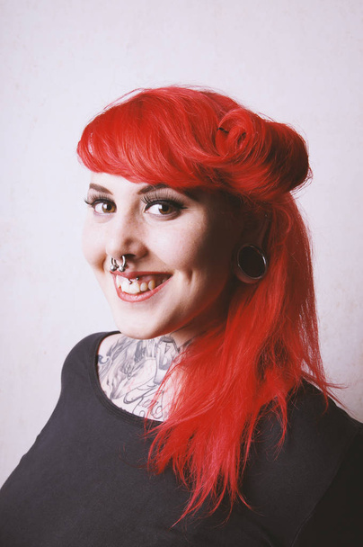 mujer joven perforada y tatuada con sonrisa dentada
 - Foto, imagen