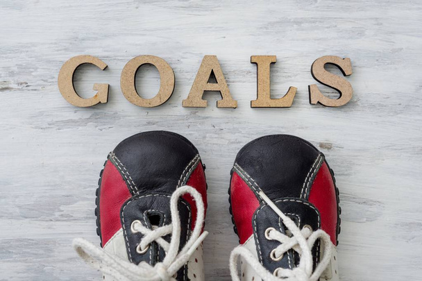 Sneakers on light surface in front of the word goals - Photo, image