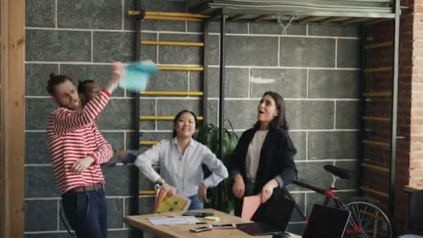 Multietnické start-up se spolupracovníky se bavit tancem v moderní kanceláři házení papírových dokumentů a slaví úspěch projektu - Záběry, video